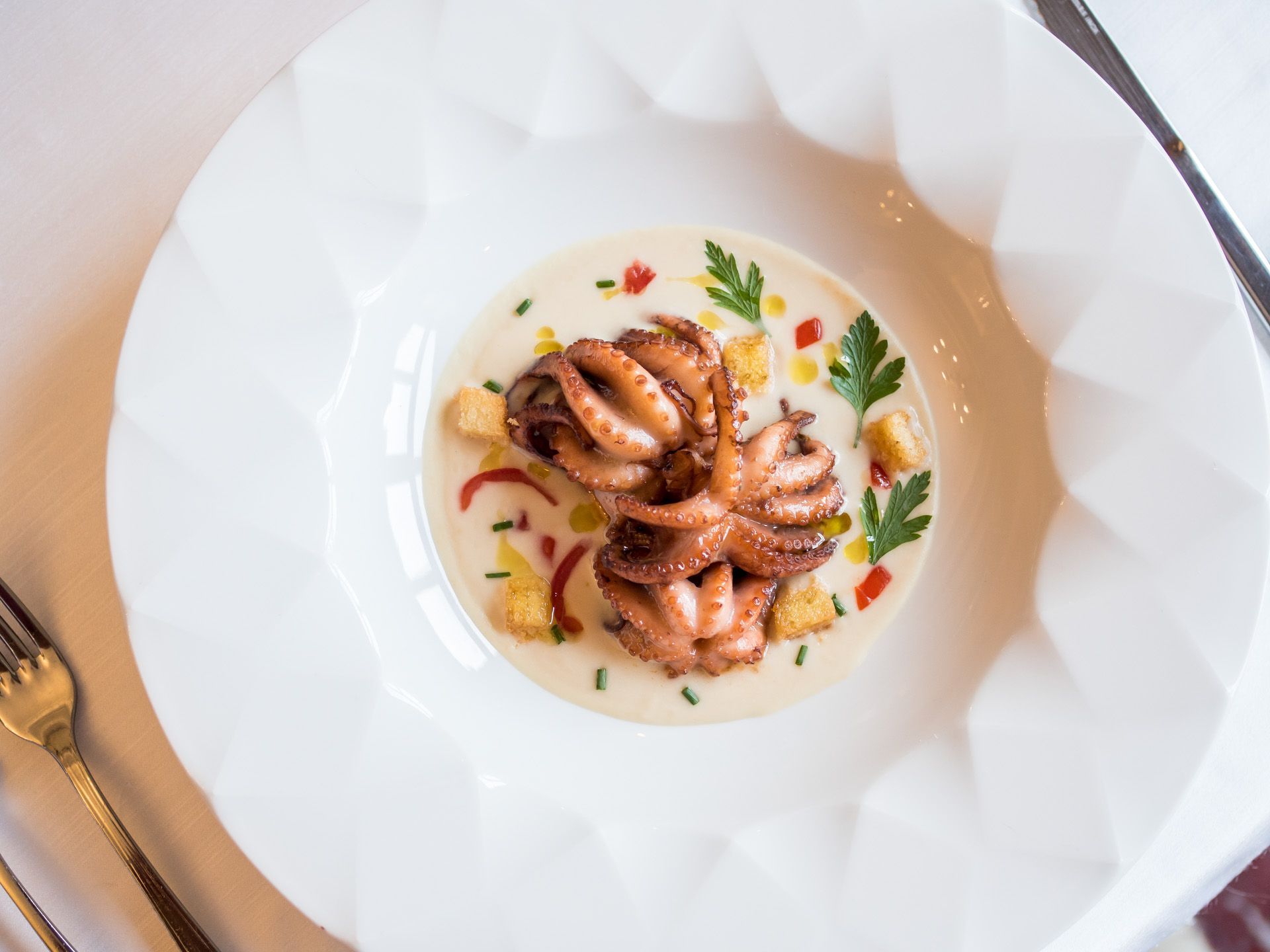 Gamberi in salsa cremosa con erbe aromatiche su un piatto bianco decorato, visti dall'alto.