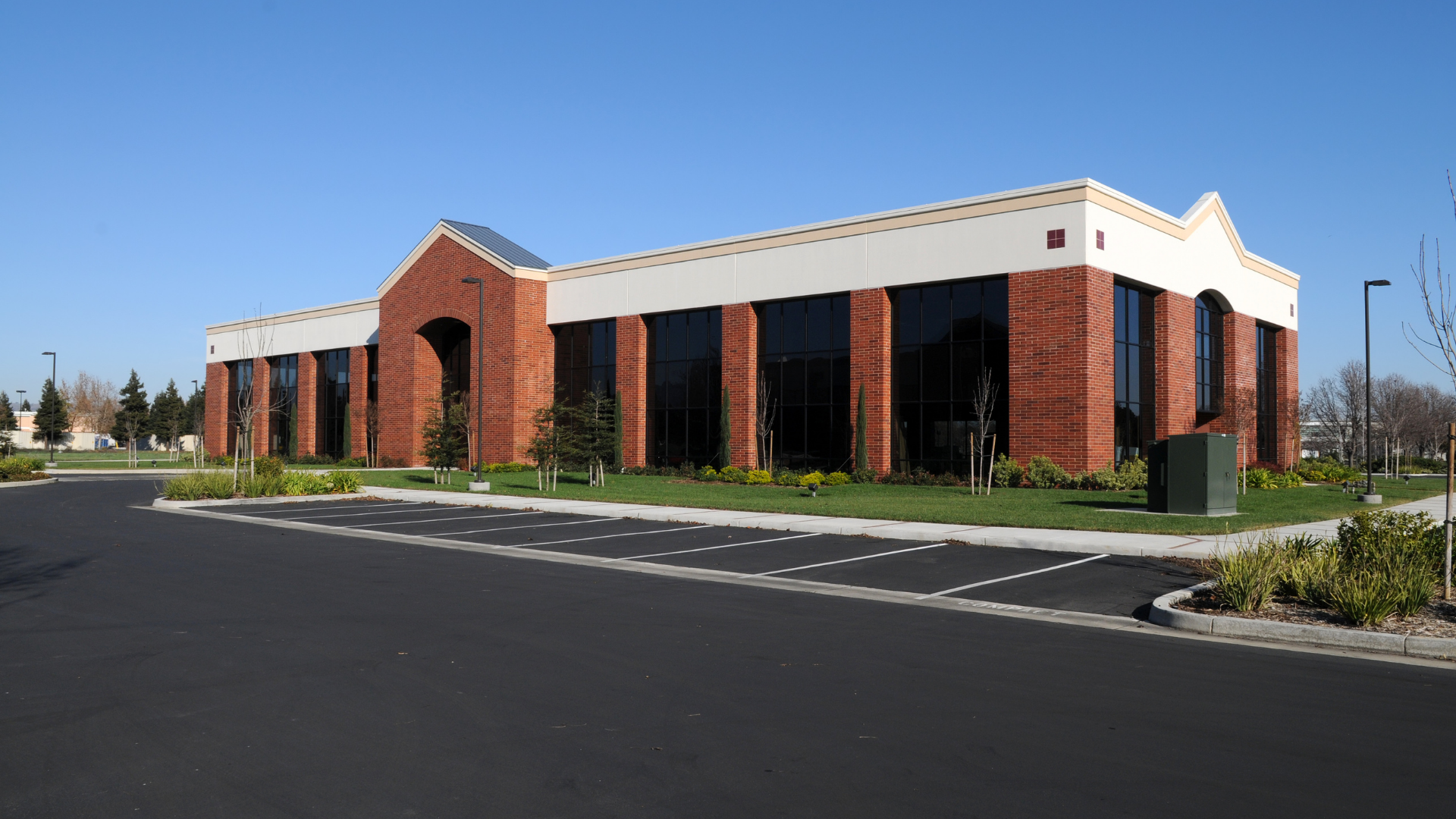 Brick building with large windows and a white trim under a clear blue sky.