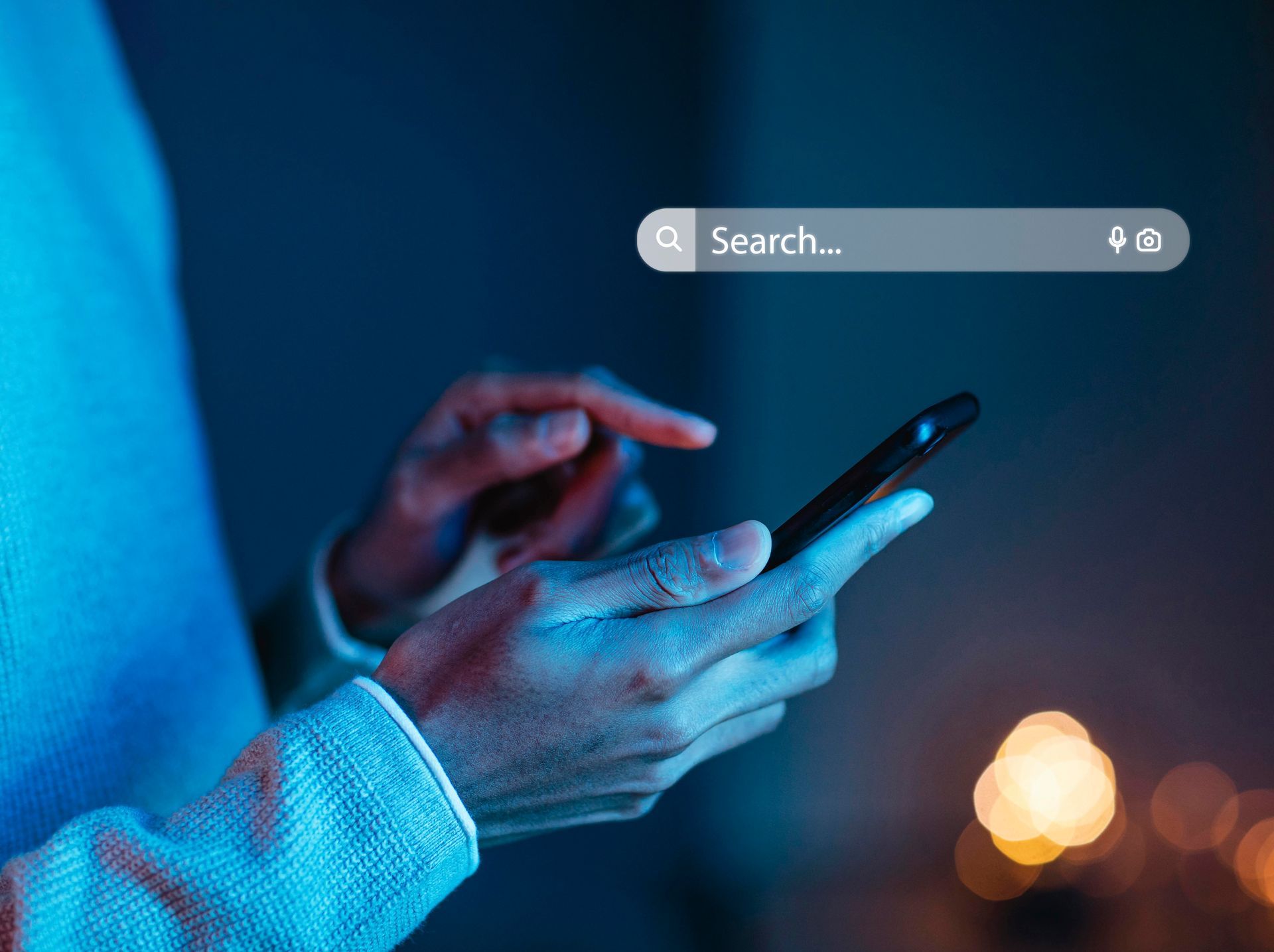 Hands using a smartphone with a search bar overlay in a blue-lit setting
