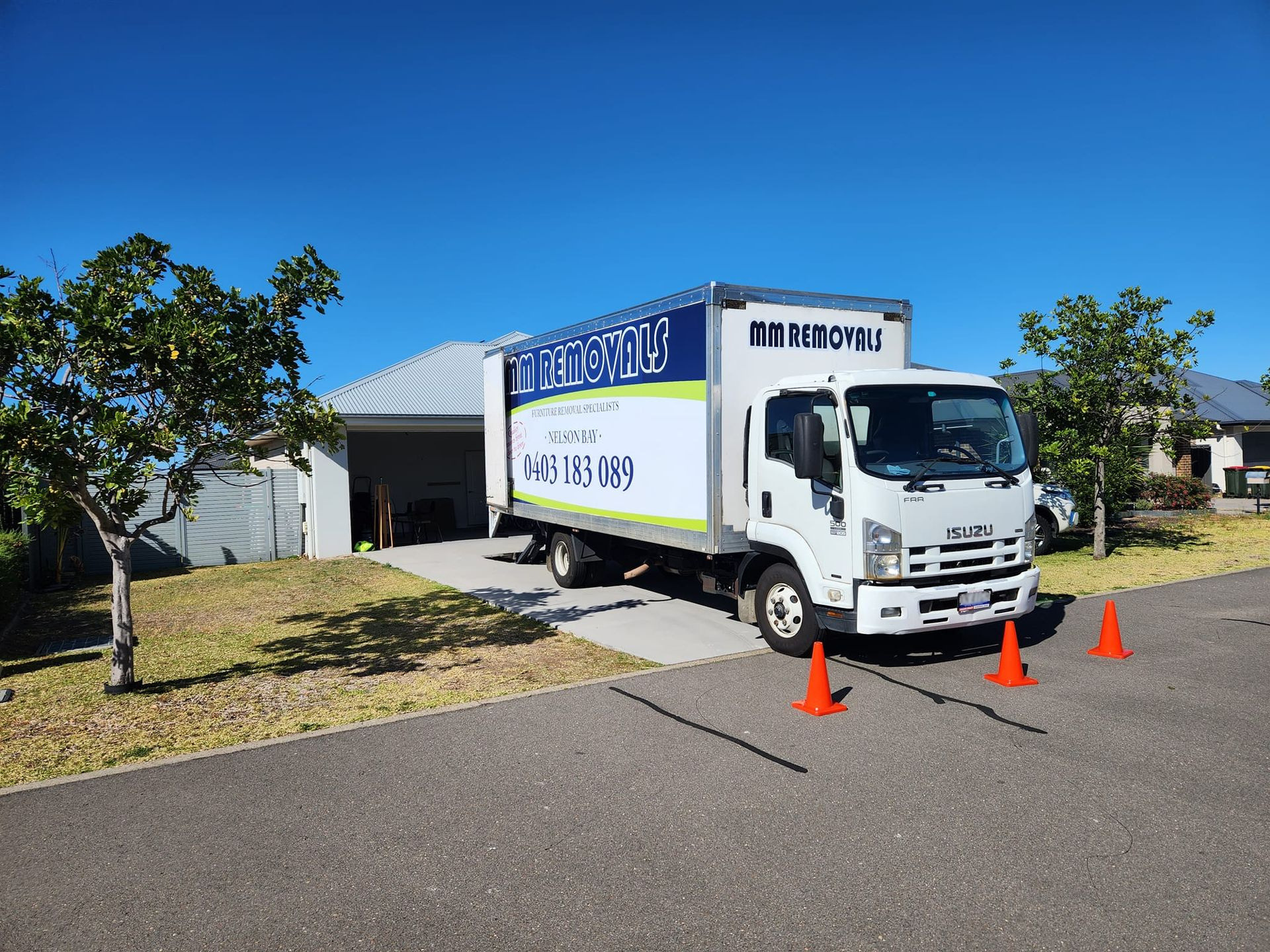 Moving Truck Parked in A Suburban Driveway with Orange Cones in Front of It — MM Removals In Nelson Bay, NSW