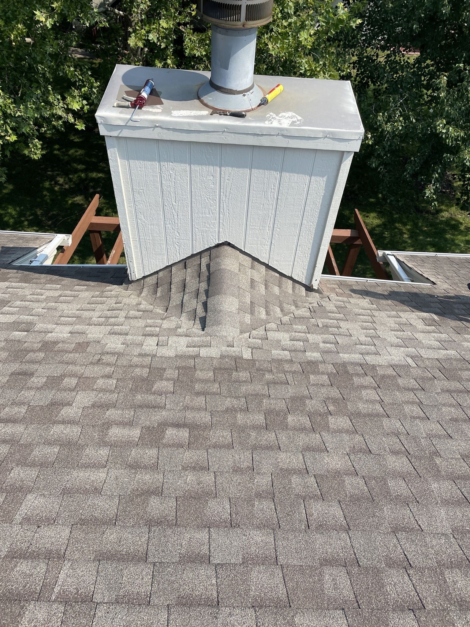 White rooftop chimney with vent pipe on a shingled roof.