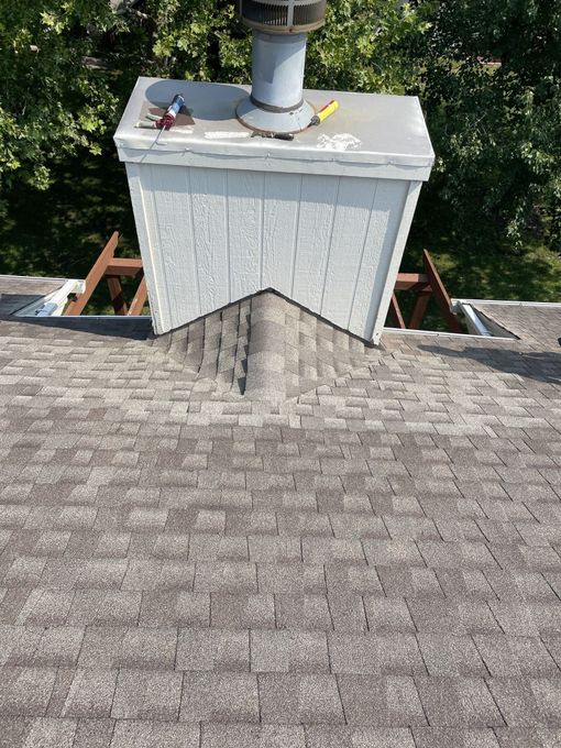 Damaged roof shingles on a beige house under a clear blue sky
