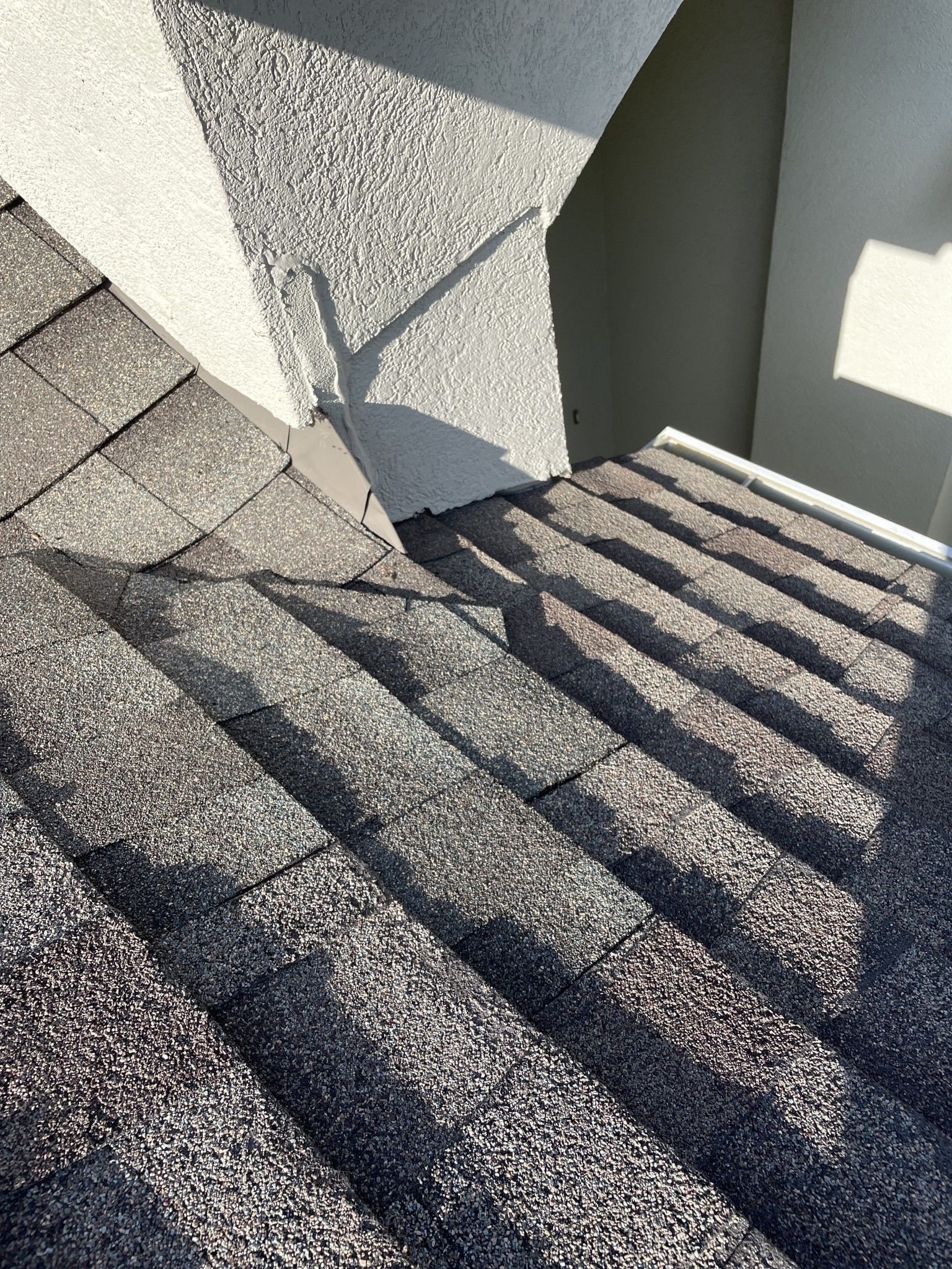Concrete stairwell with sunlit shadows and a gray wall.