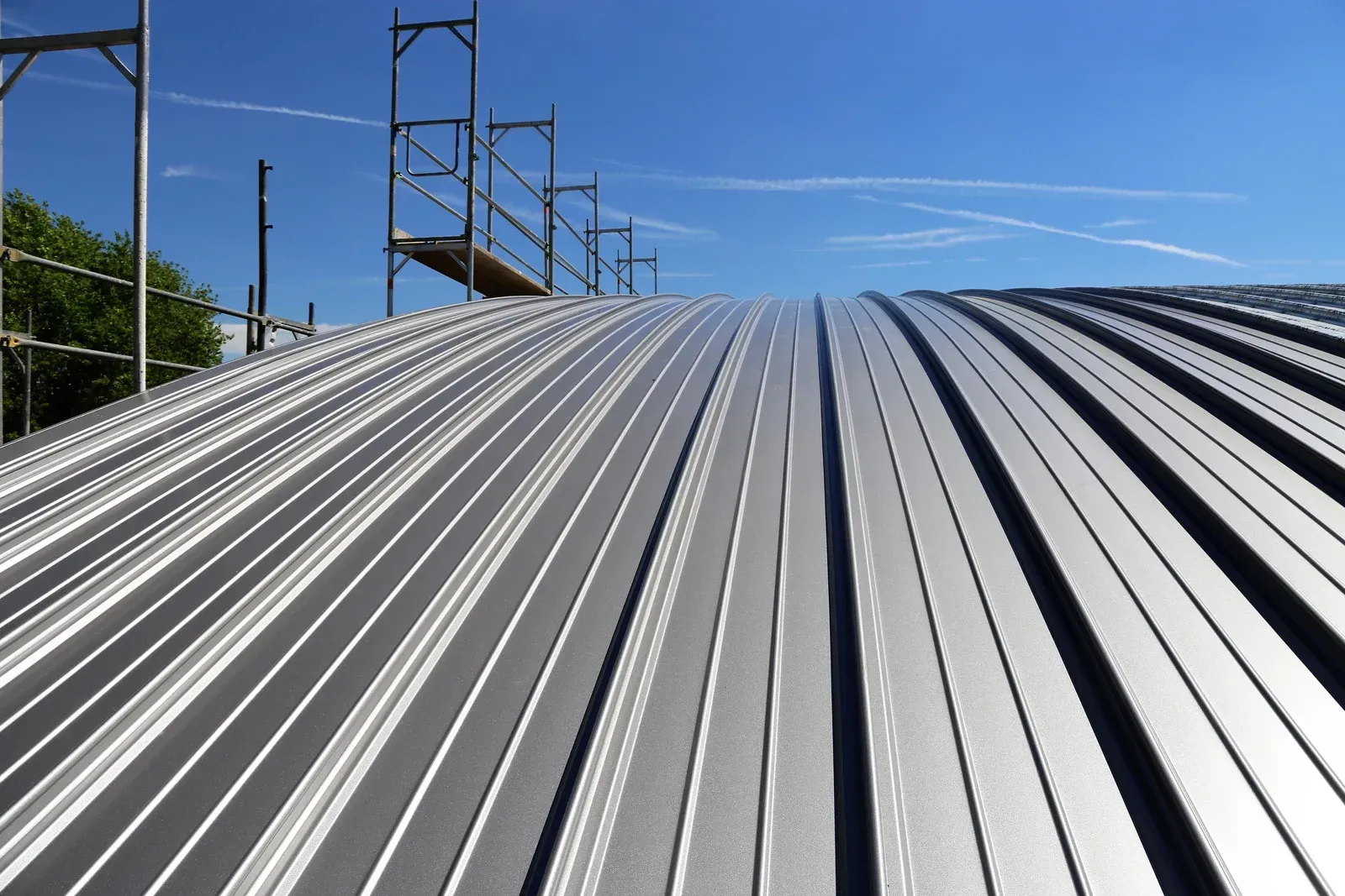 Corrugated metal roof under construction with scaffolding against a blue sky