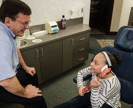 Dr. Lambert with a young patient holding a giant toothbrush, Bethlehem, PA