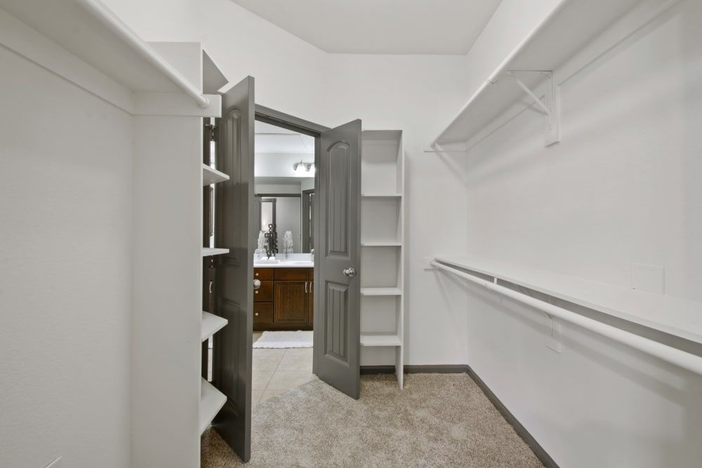 a walk-in closet with a bathroom in the background at Marquis on Evans in San Antonio, TX.