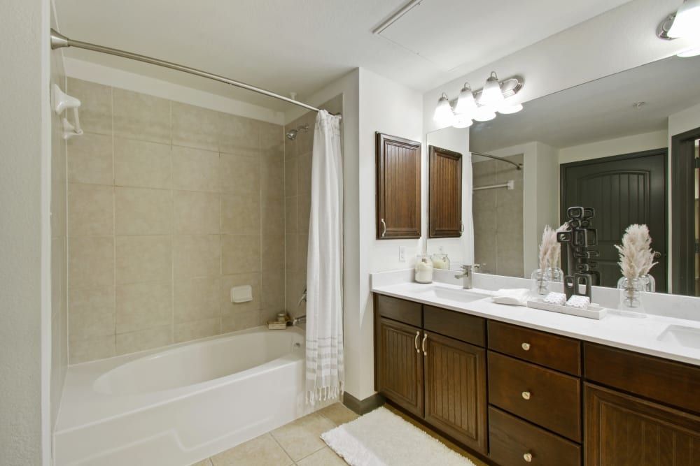 a bathroom with two sinks, a tub, and a mirror at Marquis on Evans in San Antonio, TX.