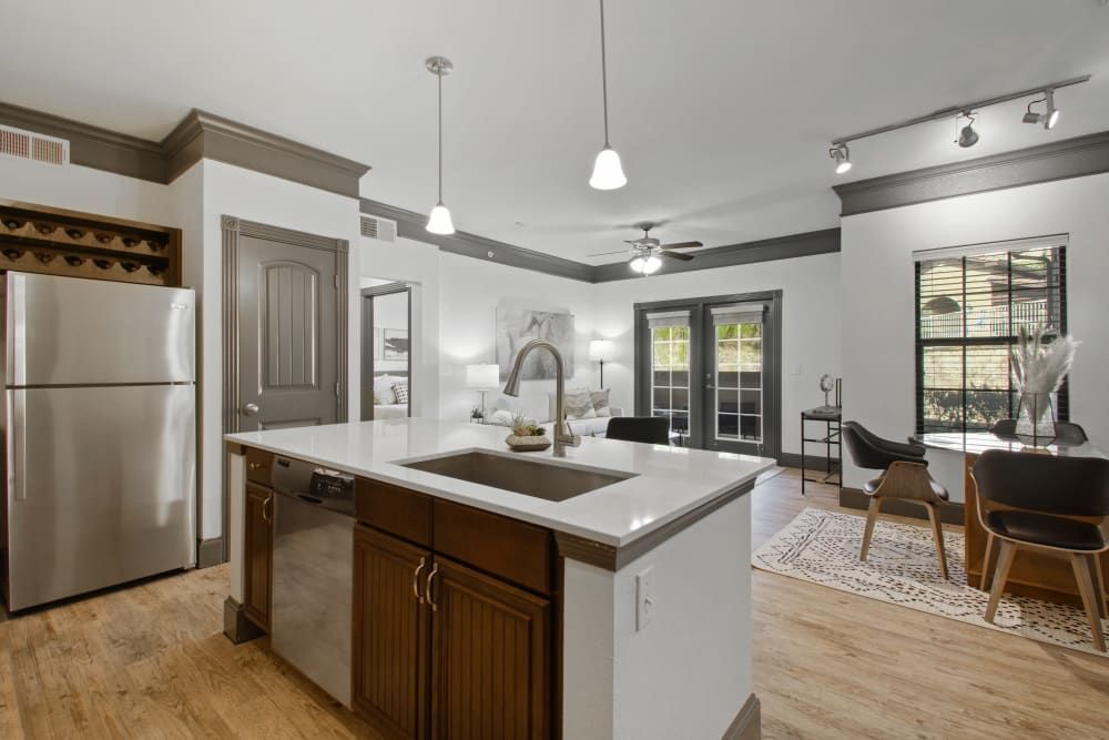 a kitchen with a stainless steel refrigerator, sink, dining table, and chairs at Marquis on Evans in San Antonio, TX.