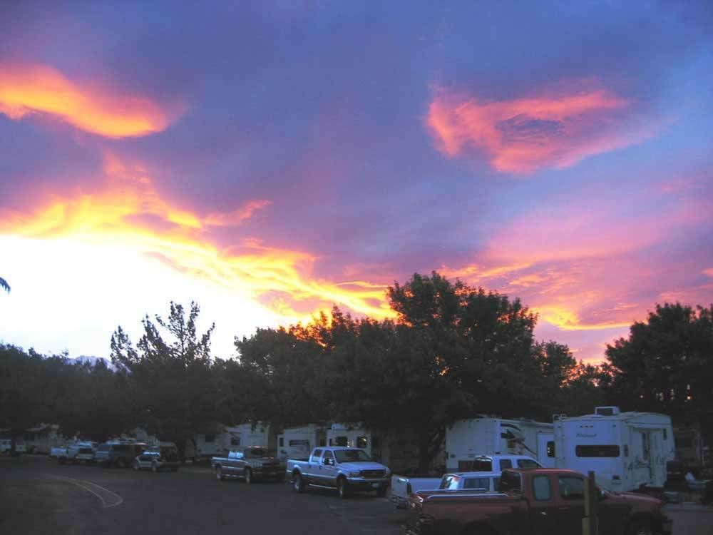 A sunset with a lot of cars parked on the side of the road