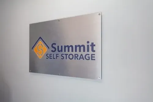 Silver wall sign reading “Summit Self Storage” with blue and orange logo