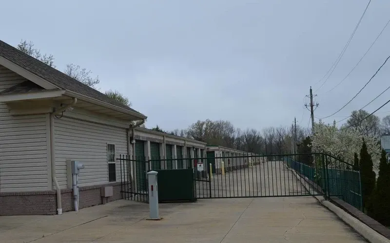 Long corridor in a storage facility with rows of closed metal unit doors on both sides.