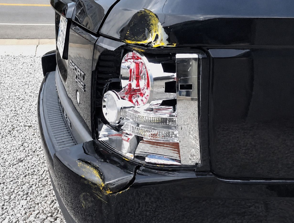 Close-up of a black car’s damaged rear taillight and bumper after a collision.