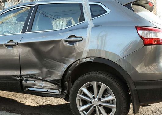 Gray SUV with severe side damage on the rear door and fender after a collision