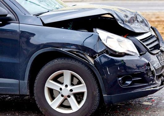 Damaged blue car with crushed front end and broken bumper after a collision