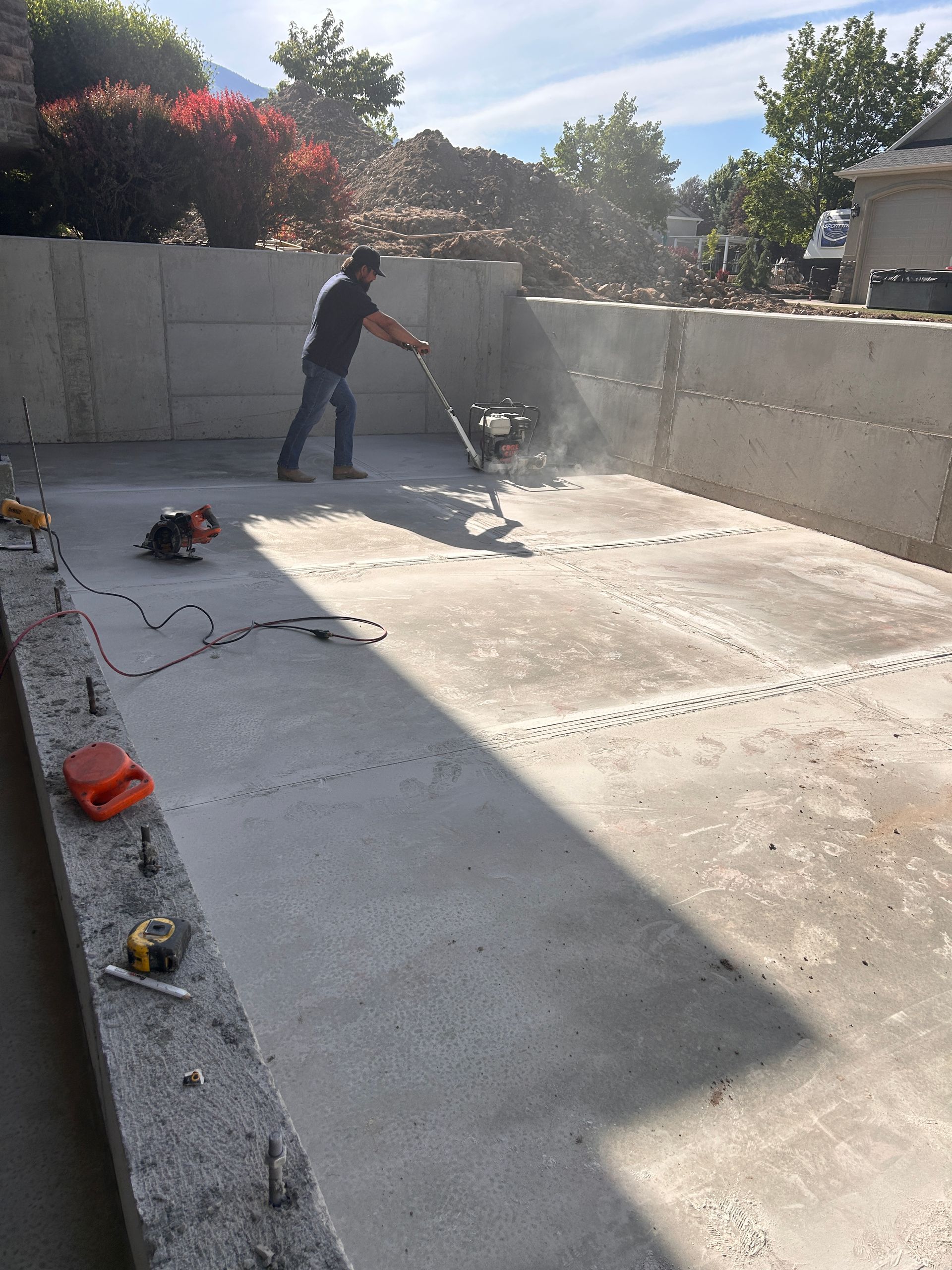 A person uses a floor grinder on a concrete surface within a walled construction area.