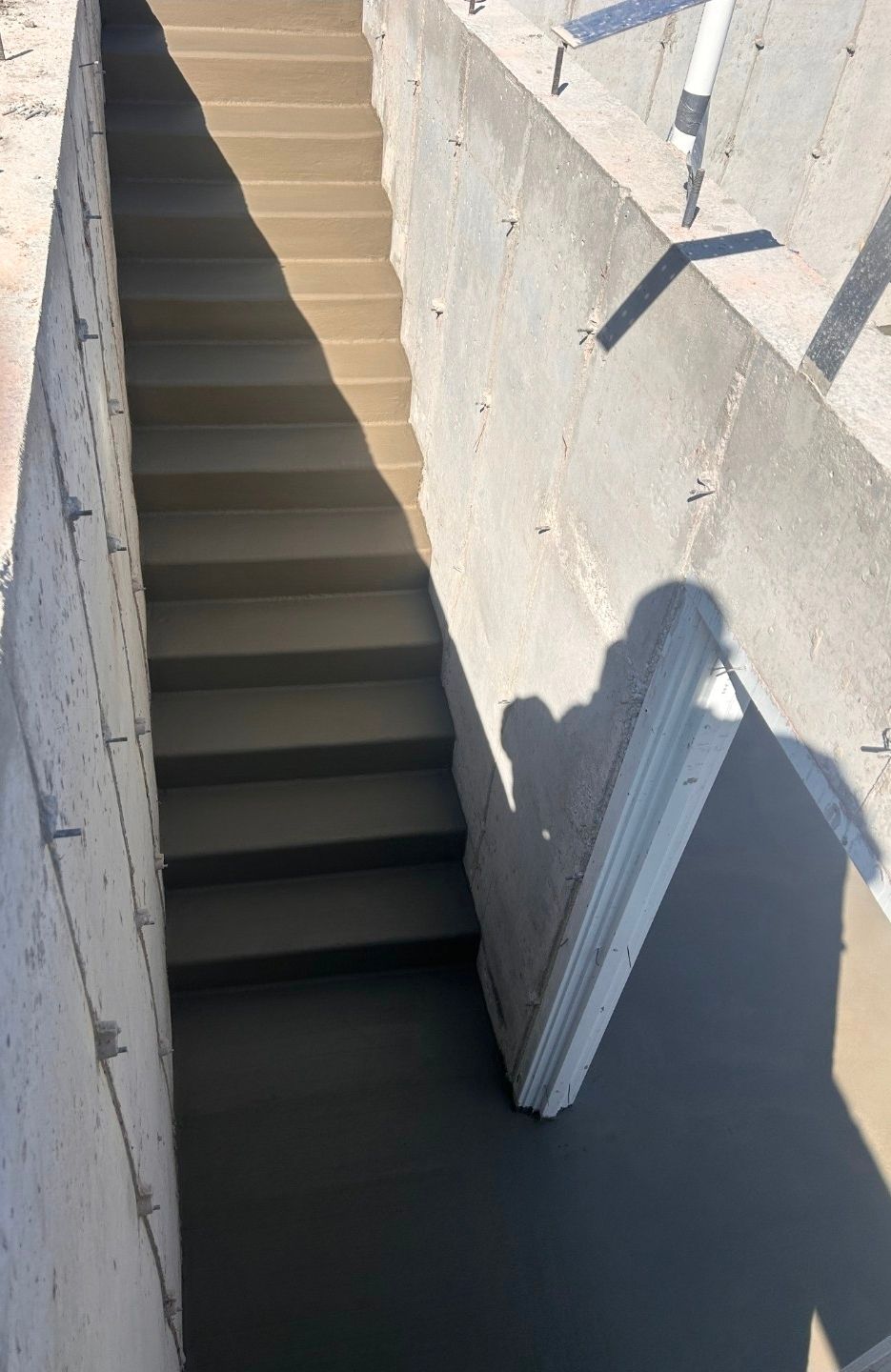 A set of freshly poured concrete stairs leading down into a basement or outdoor stairwell.