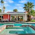 Modern house with a turquoise pool and hot tub, palm trees, and a sunny backyard patio.