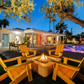 Modern backyard patio with fire pit, yellow chairs, and a lit pool at dusk