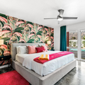 Bright bedroom with floral accent wall, gray bed, pink accents, ceiling fan, and sliding doors to outdoors