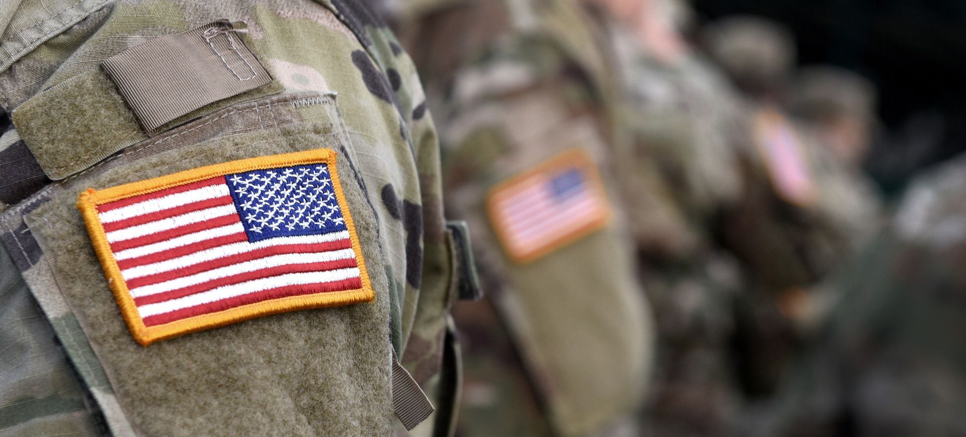 Close-up of a military uniform shoulder patch with an American flag and camouflage fabric