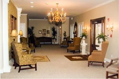 Elegant hotel lobby with chandelier, beige chairs, and sofa in a carpeted hallway