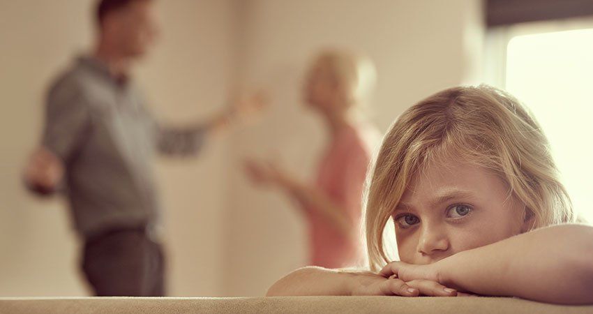 young child in foreground of parents arguing