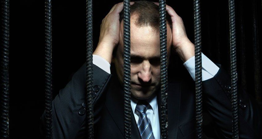man in suit behind jail cell bars