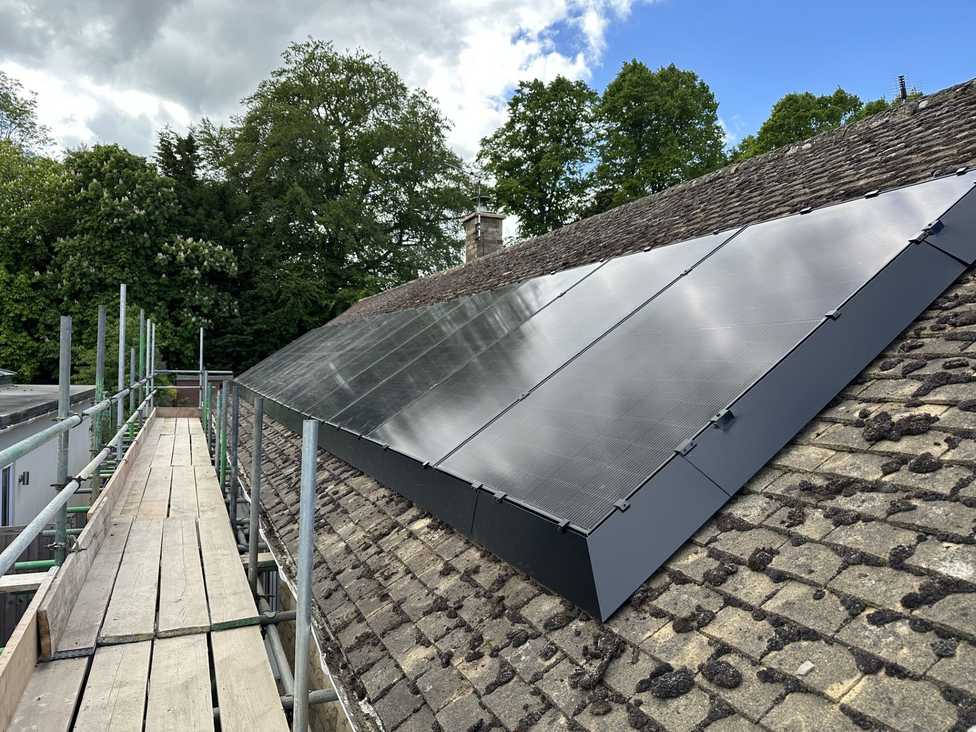 Solar panels fitted on the flat roof and gable wall of a renovated home near Iffley