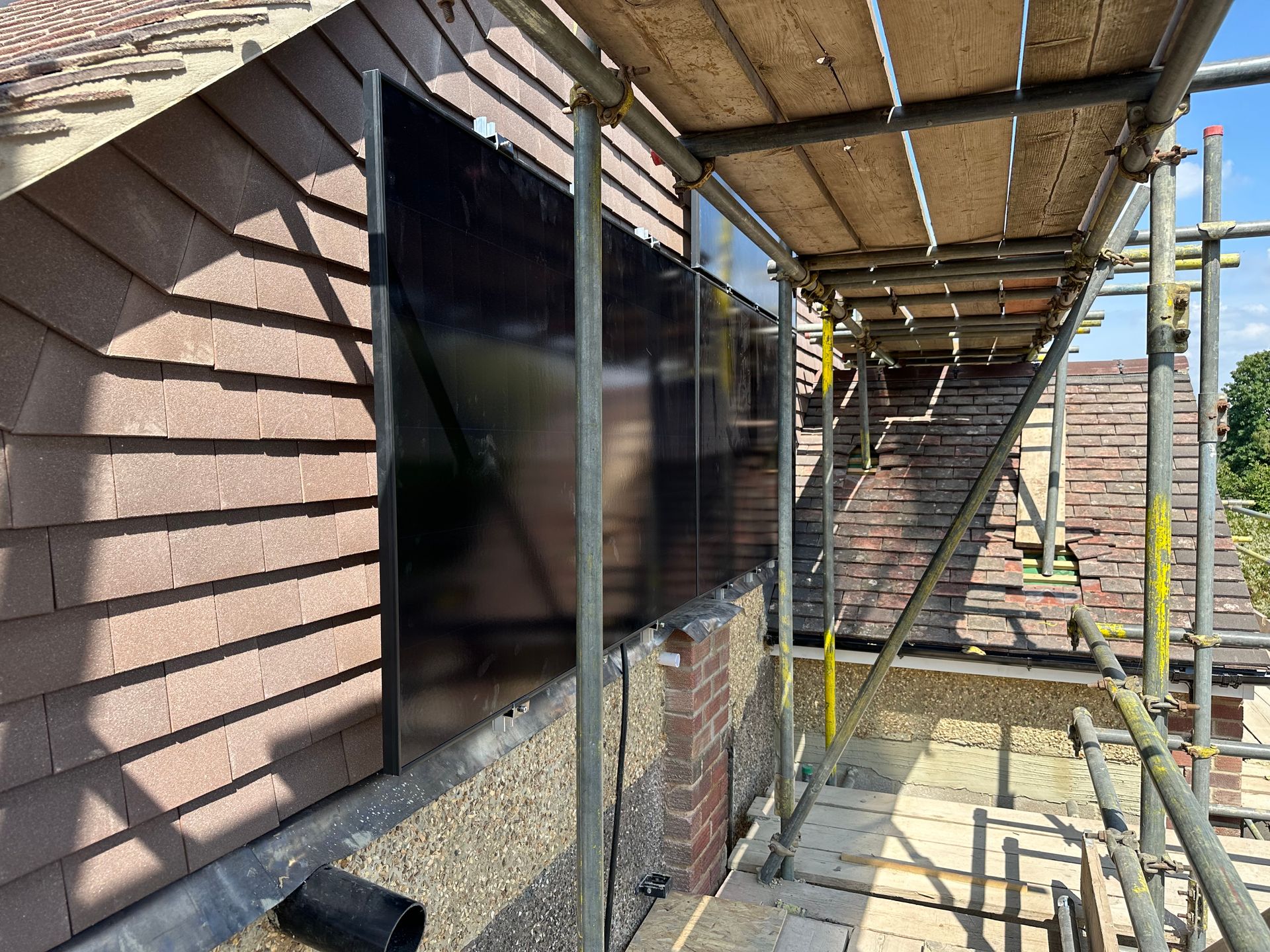Solar panels fitted on the flat roof and gable wall of a renovated home near Iffley