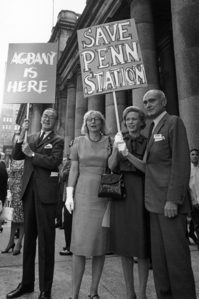 A group of people holding signs that say save penn station