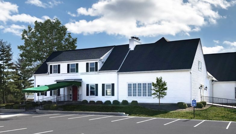 a large white house with a black roof and a green awning