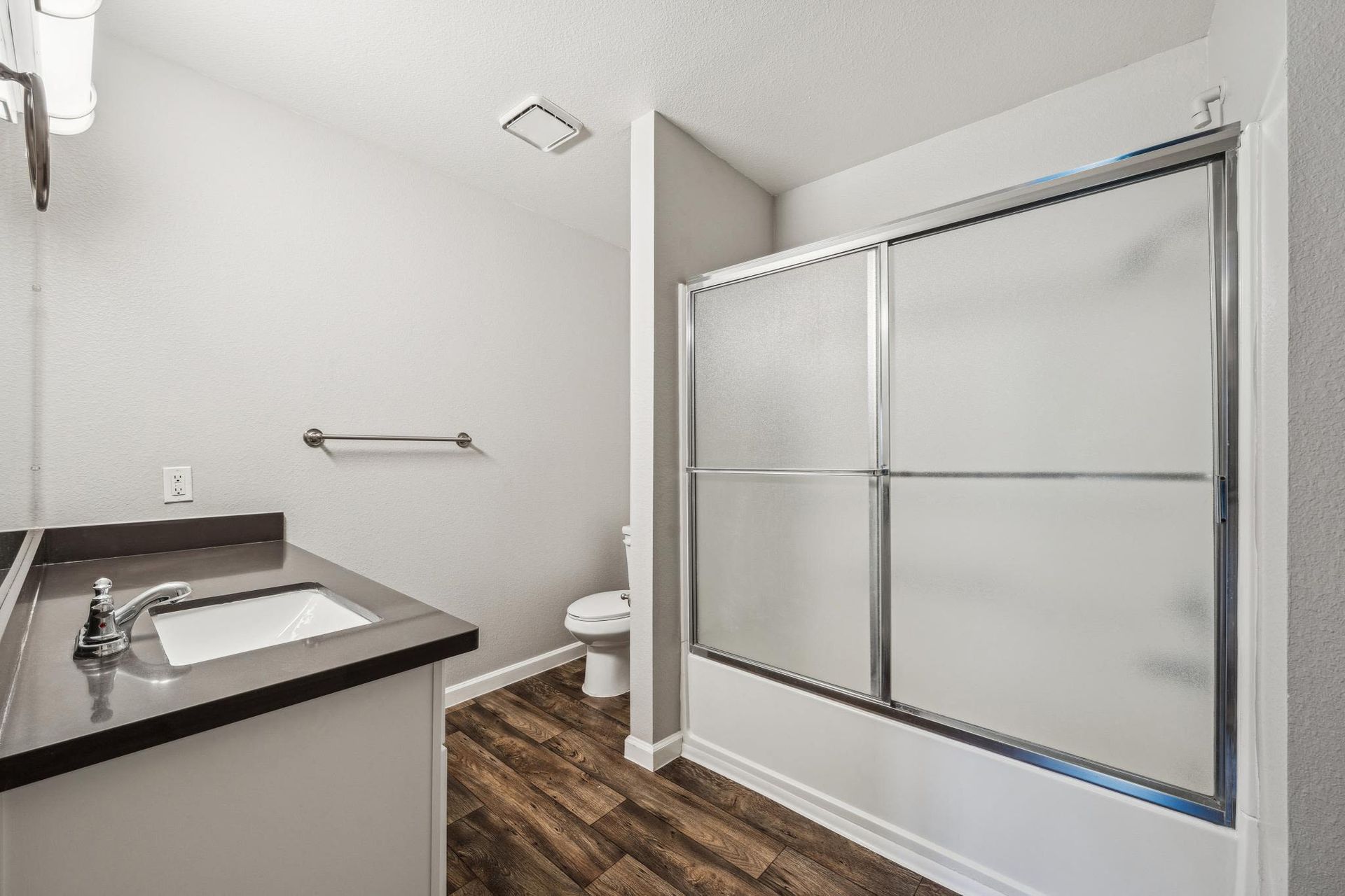 Bathroom with a single vanity, sink, toilet, and frosted sliding shower door at Sterling Heights apartments in Benicia, CA.