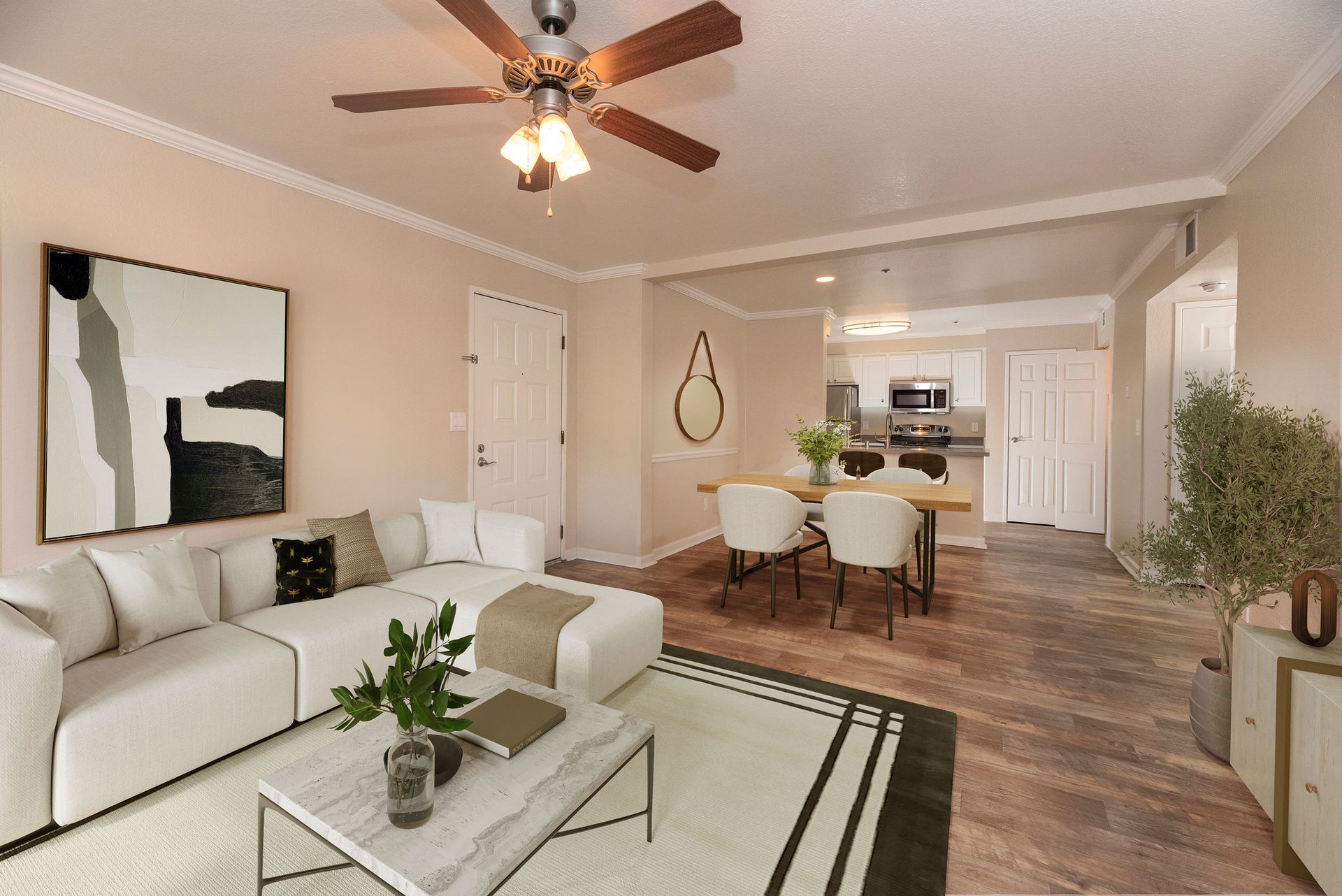 Open living area with a white sectional sofa, coffee table, dining table, and kitchen in the background at Sterling Heights apartments in Benicia, CA.