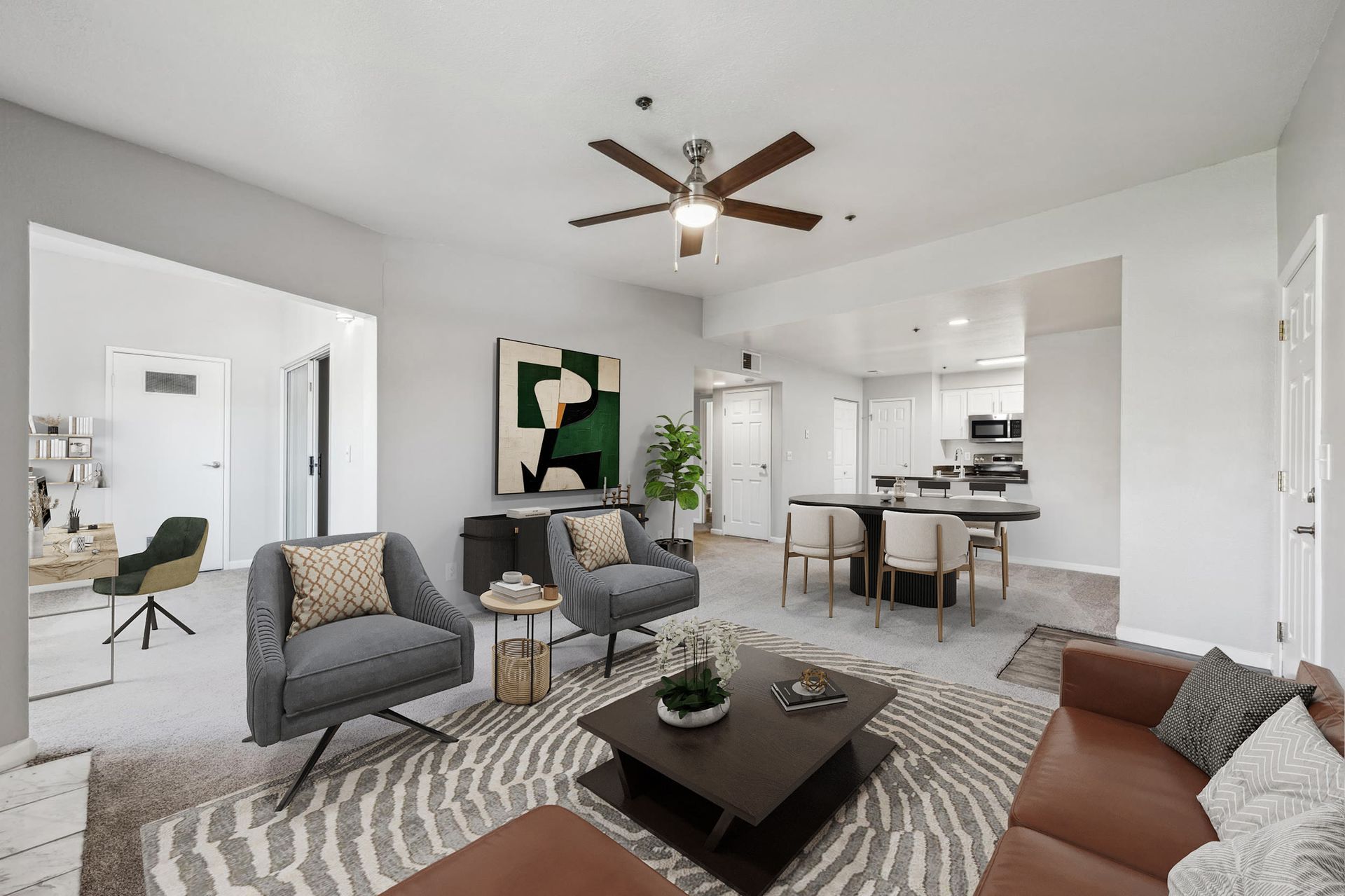 Open-concept living room with gray seating, a patterned rug, and a dining area near the kitchen at Sterling Heights apartments in Benicia, CA.