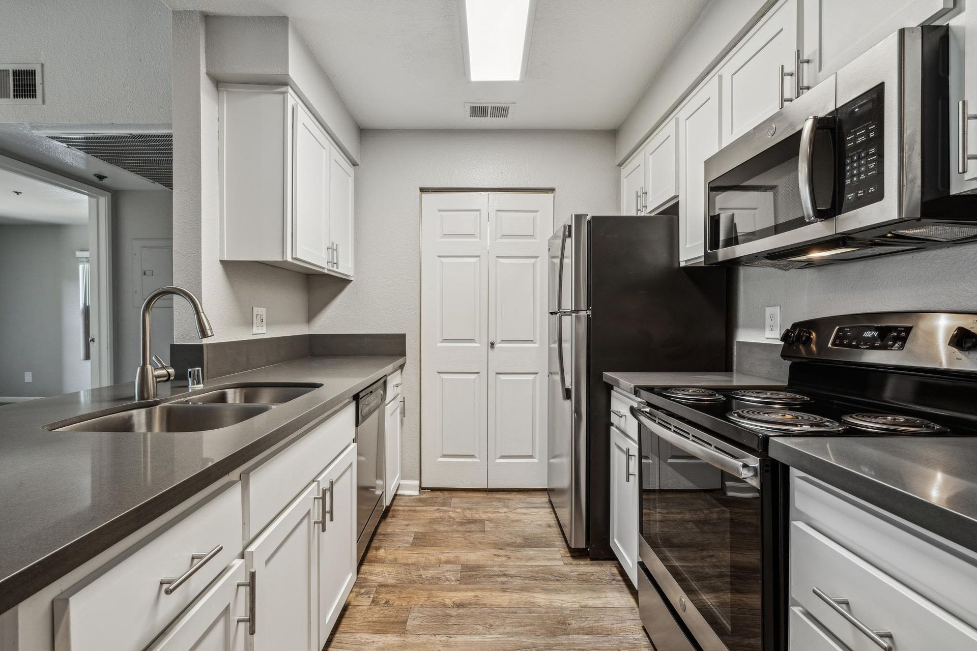 Modern apartment kitchen with stainless steel appliances, white cabinets, and gray countertops at Sterling Heights apartments in Benicia, CA.