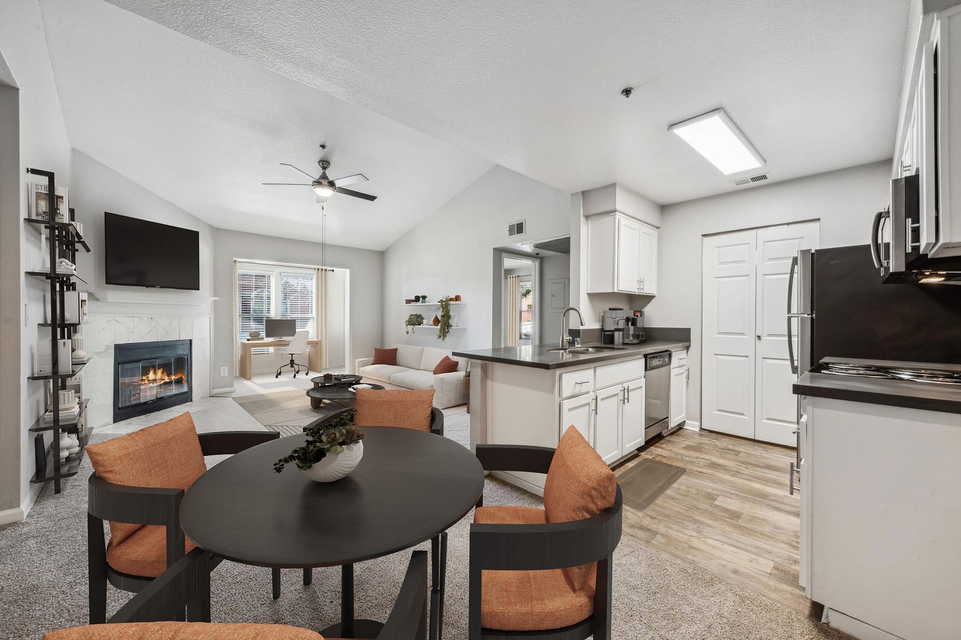 Open-concept living area with a fireplace, dining table, and a modern kitchen at Sterling Heights apartments in Benicia, CA.