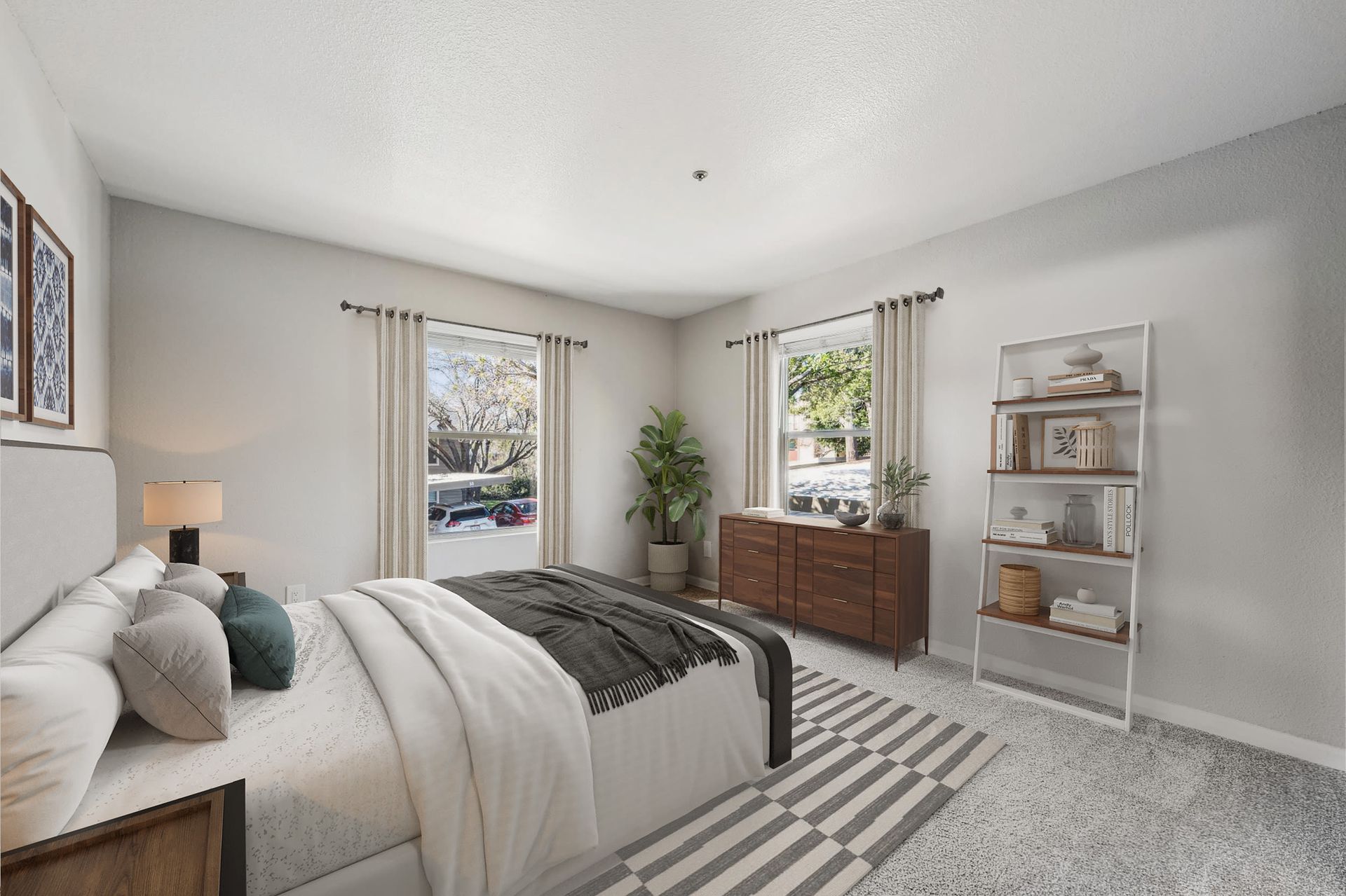 Bright bedroom in a modern apartment with a bed, dresser, plant, and white ladder bookshelf at Sterling Heights apartments in Benicia, CA.