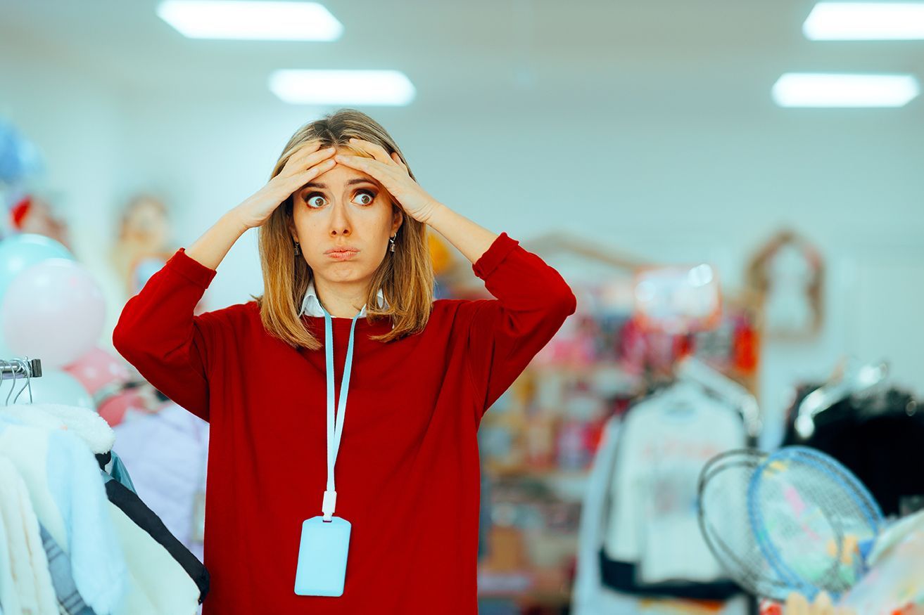 Person in a red sweater adjusts a hat in a bright clothing store.