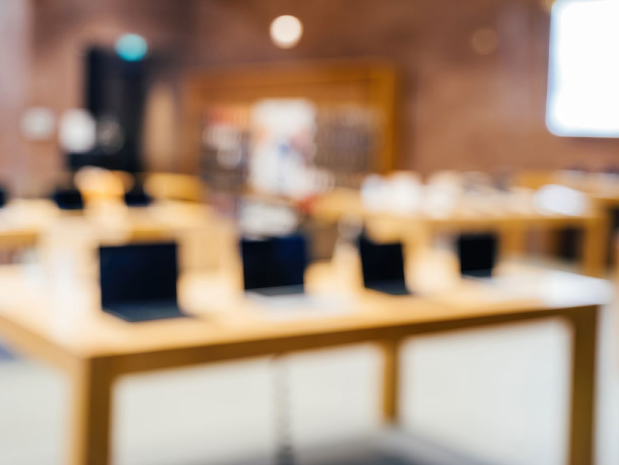 Blurred classroom with wooden tables and laptops in a warm-lit room