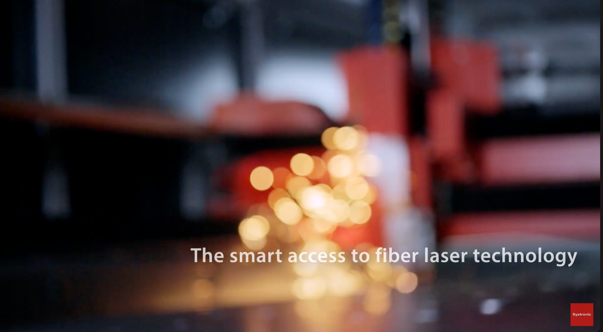 Blurred laser cutting machine with bright orange sparks and text: “The smart access to fiber laser technology”
