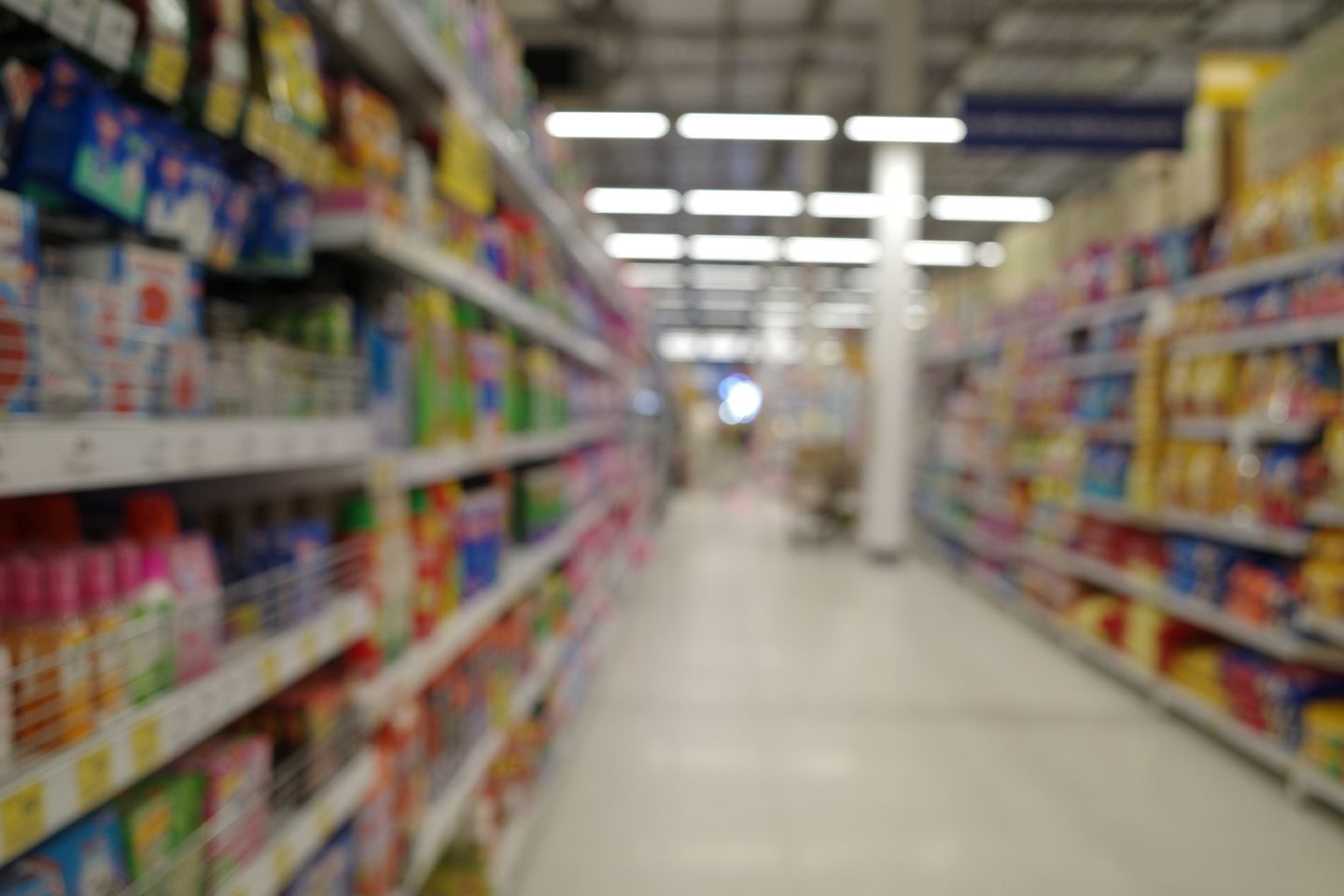 Blurred supermarket aisle with shelves of colorful products on both sides