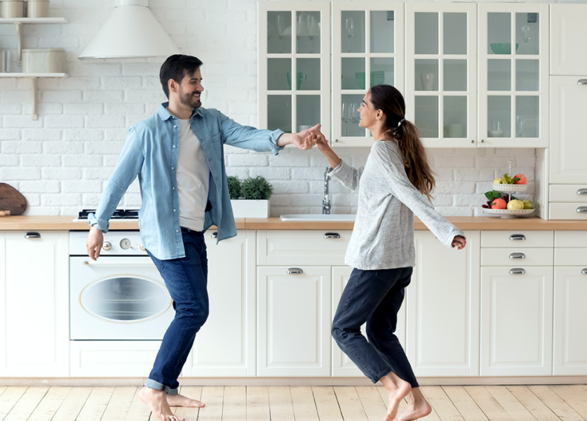A man and a woman are dancing in a kitchen.