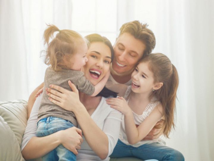 A family is sitting on a couch hugging each other and smiling.