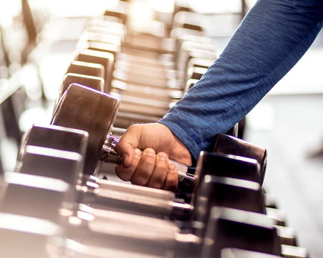 A person is holding a dumbbell in a gym.