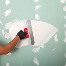 A person is plastering a wall with a spatula.