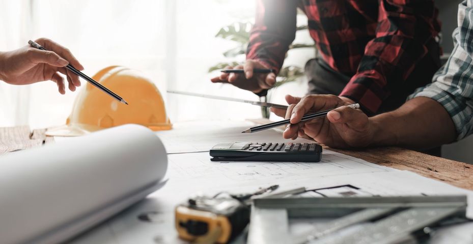 A group of construction workers are sitting at a table looking at a blueprint.
