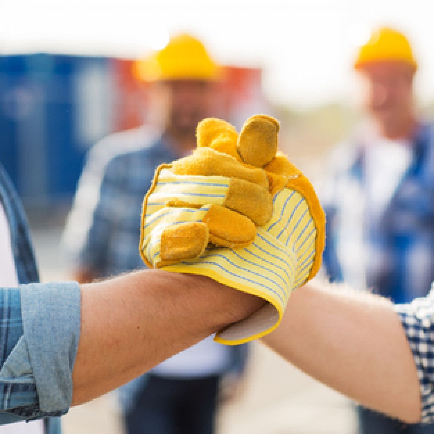 A man wearing a yellow glove is shaking hands with another man