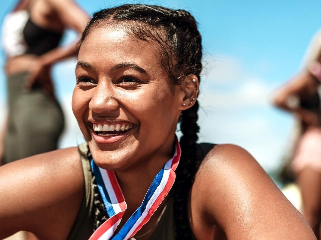 A woman wearing a medal around her neck is smiling.