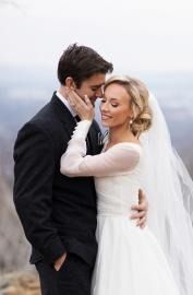 Bride and groom embracing outdoors, touching faces in a romantic wedding portrait