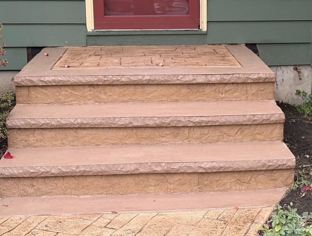 Three tan concrete steps leading to a front door on a green house with red trim